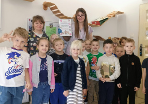 pamiątkowe zdjęcie dzieci z pnią weterynarz i asystentką. Pani weterynarz trzyma kartę z podziękowaniami.