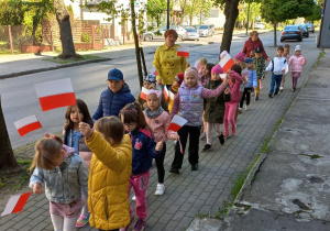 Dzieci trzymają flagi Polski samodzielnie wykonane i maszerują ulicami naszego miasta.