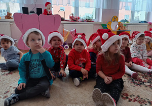 Maluszki w mikołajkowych czapkach czekają na Mikołaja.