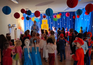 Przedszkolaki zebrane w sali balowej, słuchają instrukcji do tańca , wydawanych przez Pana Wodzireja.