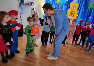 Przedszkolaki zebrane w sali balowej, słuchają instrukcji do tańca , wydawanych przez Pana Wodzireja.