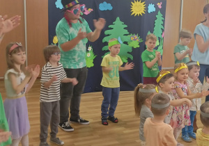 Mężczyzna w kapeluszu i okularach w kształcie serca klaszcze razem z dziećmi.