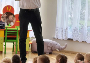 Mężczyzna w białej koszuli gra na rogu, instrumencie dętym.