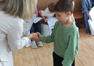 Tymek z grupy 6-latków odbiera z rąk Pani Dyrektor swoje nagrody za udział w wystawie.