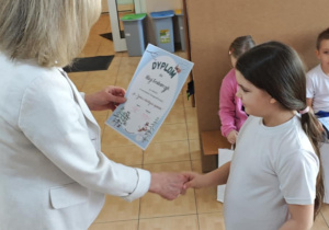 Ala z grupy 6-latków odbiera z rąk Pani Dyrektor swoje nagrody za udział w wystawie.