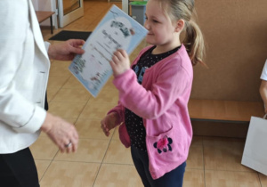 Klara z grupy 6-latków odbiera z rąk Pani Dyrektor swoje nagrody za udział w wystawie.