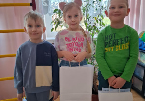 Troje dzieci z grupy Motylków pozuje do wspólnego zdjęcia ze swoimi nagrodami i dyplomami.