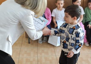 Nokoloz z grupy 4,5-latków odbiera z rąk Pani Dyrektor swoje nagrody za udział w wystawie.
