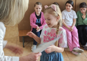 Nela z grupy 5-latków odbiera z rąk Pani Dyrektor swoje nagrody za udział w wystawie.