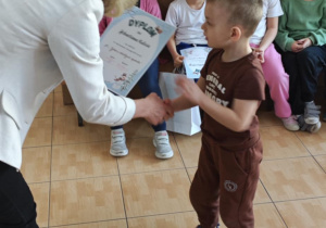 Sebastian z grupy 4-latków odbiera z rąk Pani Dyrektor swoje nagrody za udział w wystawie.