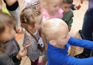 Dzieci przypinają pomarańczowe serduszka na Drzewie Przyjaźni.