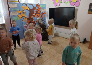 Pani Ewa przypina z Jagódkami serduszka z ich imionami na Drzewie Przyjaźni.