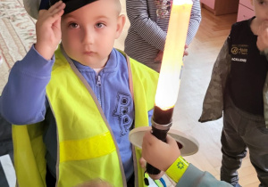 Chłopiec przymierza czapkę policjanta za nim zaciekawiona dziewczynka.