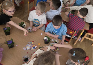 Sadzenie bratków przy stoliczkach pod nadzorem prowadzących warsztaty.