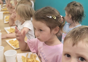 Maluszki jedzą frytki z keczupem.
