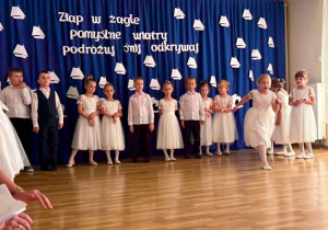 Recytowanie wierszy i śpiewanie piosenek okolicznościowych na tle dekoracji z okazji zakończenia przedszkola.