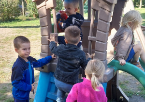 Dzieci wspinają się na zjeżdżalnię w ogrodzie przedszkolnym.