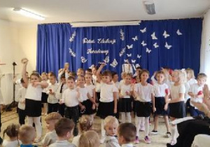 Przedszkolaki tańczą taniec. Każde dziecko trzyma instrument marakas, albo dzwoneczki muzyczne.