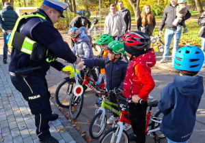 Policjant rozdaje dzieciom odblaski.