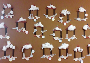 Karmniki z papieru, przyklejone na nich obrazki ptaków. Na karmniku wata imitująca śnieg. Prace wykonane przez dzieci.