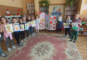 6-latki stoją w półkolu i trzymają namalowane przez siebie portrety Babć i Dziadków.