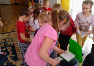 Dzieci wrzucają obrazki z narysowanymi odpadami do odpowiedniego koloru koszy.