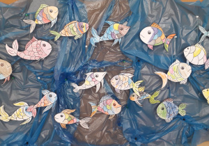 Praca pt. "Czysta rzeka". Kolorowe ryby i umieszczone na tle niebieskiej folii.