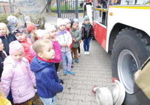 Przedszkolaki oglądają wyposażenie wozu strażackiego.