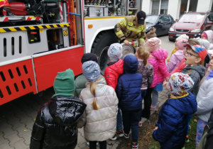 Przedszkolaki oglądają wyposażenie wozu strażackiego.