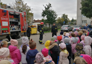 Przedszkolaki oglądają wyposażenie wozu strażackiego.