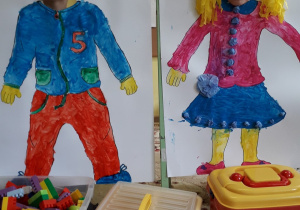 Namalowana postać chłopca i dziewczynki, w miejscu na twarz buźki dzieci z grupy 5-latków.
