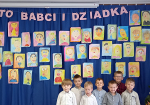 Chłopcy z grupy 4-latków na tle portretów Babć i Dziadziusiów.