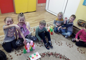 Przedszkolaki podczas zabaw kolorowymi kubkami, które układają według wzoru.