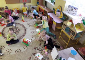 Przedszkolaki podczas zabaw kolorowymi kubkami, które układają według wzoru.