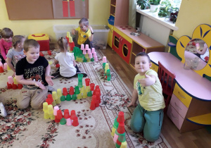 dzieci układają kolorowe budowle z kubków według własnych pomysłów.