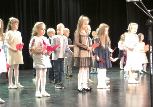 Przedszkolaki na scenie trzymają papierowe serca.
