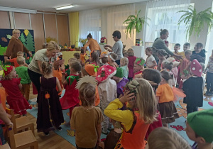 Wszystkie przedszkolaki w kolorowych, jesiennych przebraniach, tańczą do tematycznych piosenek.