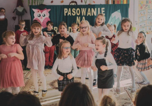 Dzieci z grupy starszaków tańczą i śpiewają piosenkę na Pasowaniu na Przedszkolaka w grupie trzylatków.