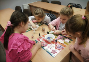 Dziewczynki z grupy Promyczki ozdabiają brokatem i cekinami serduszka i gwiazdki z masy porcelanowej.