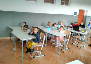 Przedszkolaki siedzą w ławkach jak na prawdziwych szkolnych lekcjach.