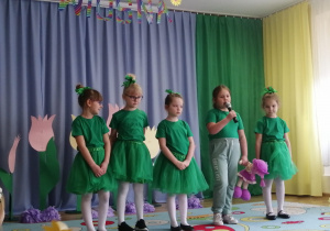 Dziewczynki w zielonych strojach recytują wiersze.