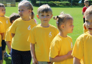 Dzieci w żółtych podkoszulkach z numerem sześć czekają na rozpoczęcie kolejnej konkurencji.