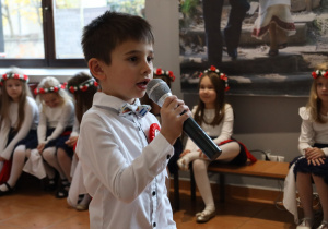 Mikołaj S.w odświętnym stroju recytuje wiersz o tematyce patriotycznej.