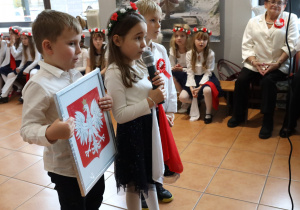 Kuba, Kornelka i Szymon prezentują godło i flagę Polski.