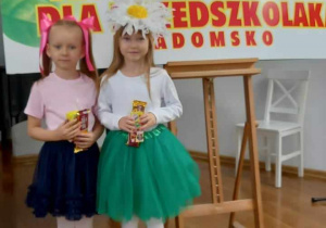 Julia i Oliwka stoją na tle reklamy festiwalu ze słodyczami.