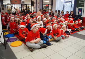 Dzieci ze wszystkich radomszczańskich przedszkoli siedzą na dywanie w oczekiwaniu na Mikołaja.