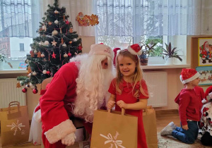 Tola pozuje do zdjęcia ze swoim prezentem i Mikołajem.