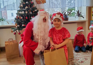 Tosia pozuje do zdjęcia ze swoim prezentem i Mikołajem.