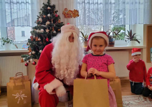 Hania H. pozuje do zdjęcia ze swoim prezentem i Mikołajem.
