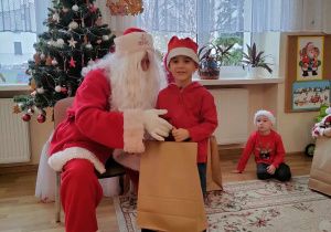 Gabryś pozuje do zdjęcia ze swoim prezentem i Mikołajem.